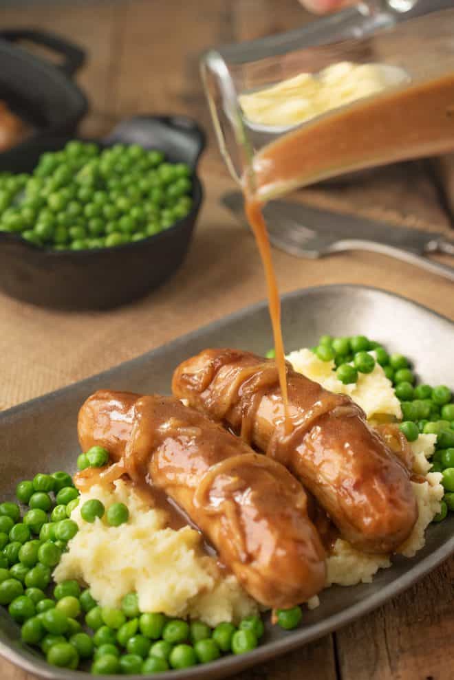 Pouring onion gravy over banger and mash