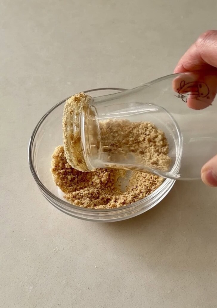 Coating the rim of a banoffee pie milkshake bottle with cookie crumbs
