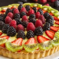 Red, black and green fruit on top of a berry custard tart