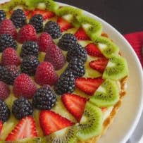 A closeup showing the top decorated with kiwi, strawberry, blackberries and raspberries