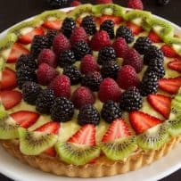 A custard tart decorated with colorful berries and kiwi