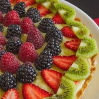 Beautiful raspberries, blackberries, strawberries and kiwi decorate a custard tart