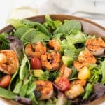 A closeup showing a perfectly charred grilled shrimp in the salad