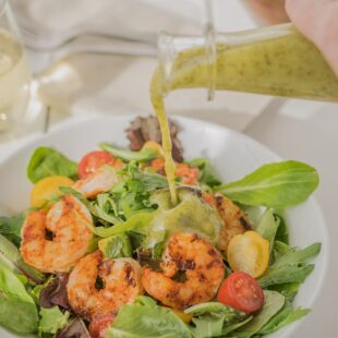 Pouring salad dressing over a shrimp salad