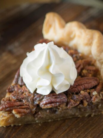 A slice of Bourbon Pecan Pie topped with whipped cream