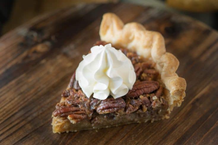 A slice of Bourbon Pecan Pie topped with whipped cream