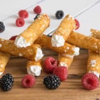 Brandy Snaps on a serving board with raspberries and blackberries
