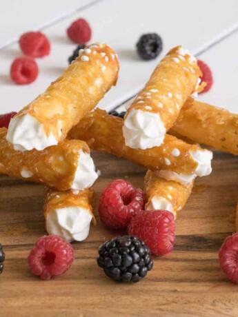 Brandy Snaps on a serving board with raspberries and blackberries
