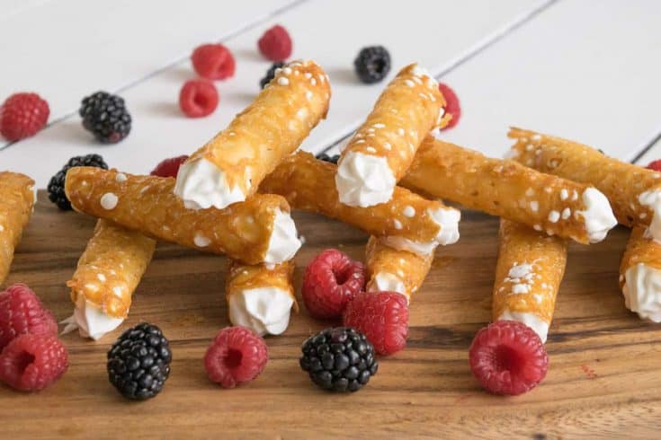 Brandy Snaps on a serving board with raspberries and blackberries