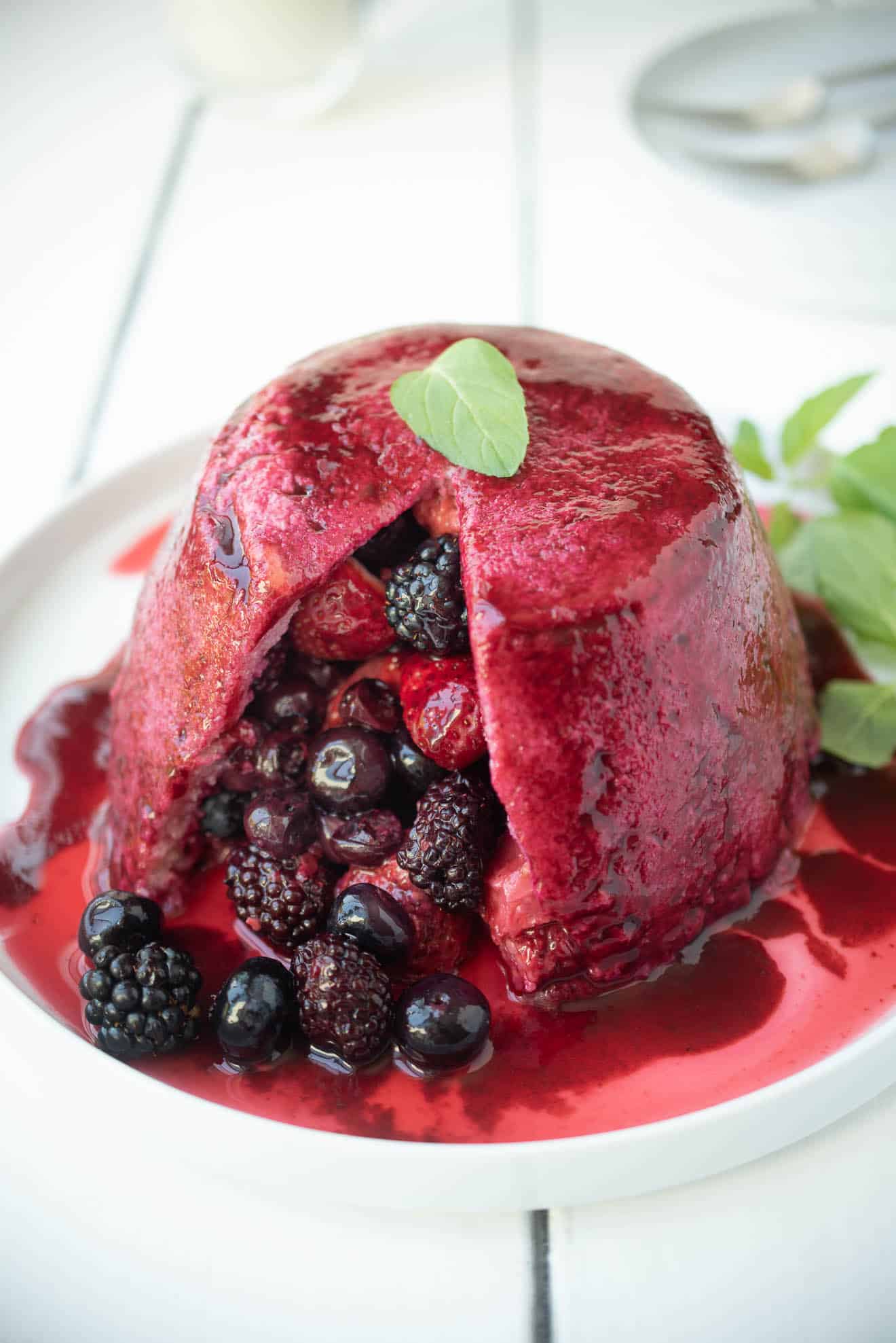 Summer pudding made from bread, opened with berries poured onto a plate