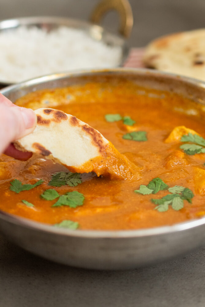 Dipping naan bread into chicken balti