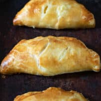 3 cheese and onion pasties lined up on a pan
