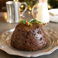 A fruity Christmas pudding on a pewter plate garnished with holly