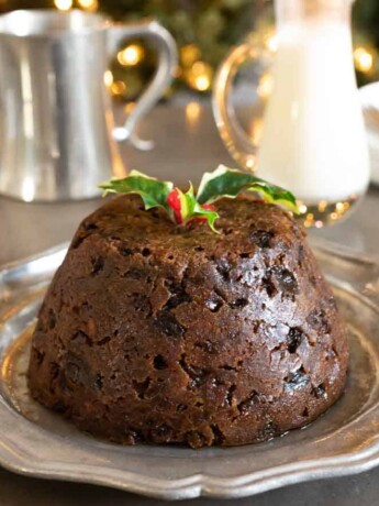 A fruity Christmas pudding on a pewter plate garnished with holly