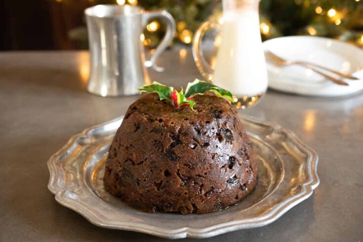 A fruity Christmas pudding on a pewter plate garnished with holly