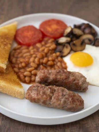 A full English breakfast with sausage, beans, fried egg, mushrooms, tomato and toast