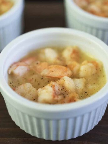 Poached shrimp in butter in a white bowl