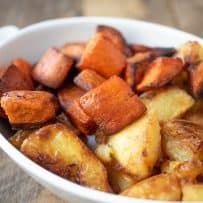 Roasted sweet potatoes/yam and regular potatoes in a white dish