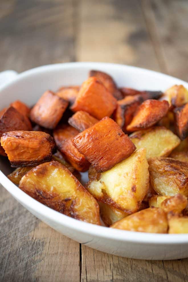Roasted sweet potatoes/yam and regular potatoes in a white dish