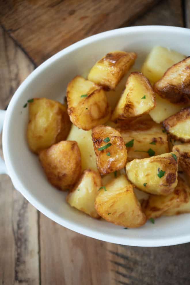 A closeup of British roast potatoes garnished with fresh parsley