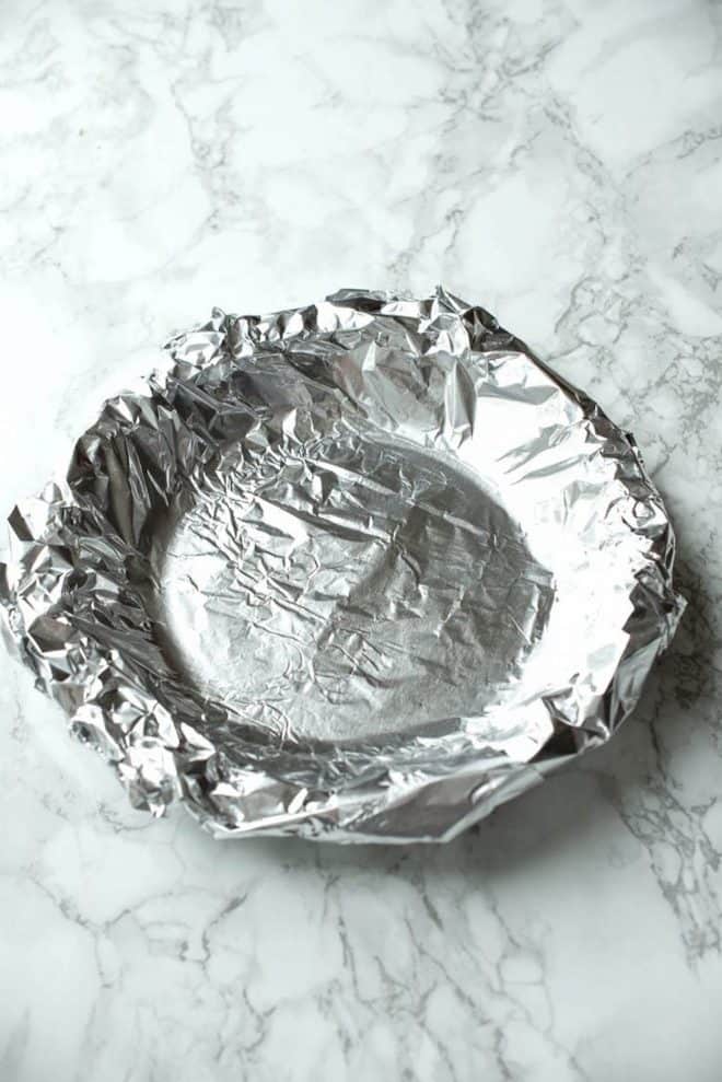 Foil covering pie crust ready to bake