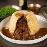 A steak and kidney pudding cut open showing the steak and kidney inside with gravy
