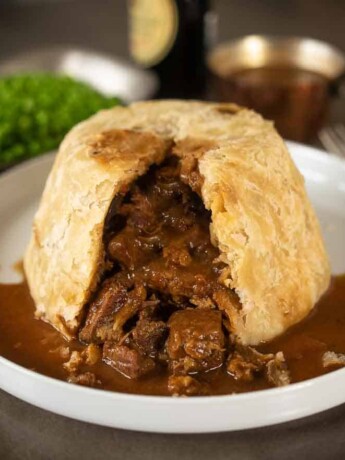 A steak and kidney pudding cut open showing the steak and kidney inside with gravy
