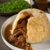 Pouring gravy over a steak and kidney pudding