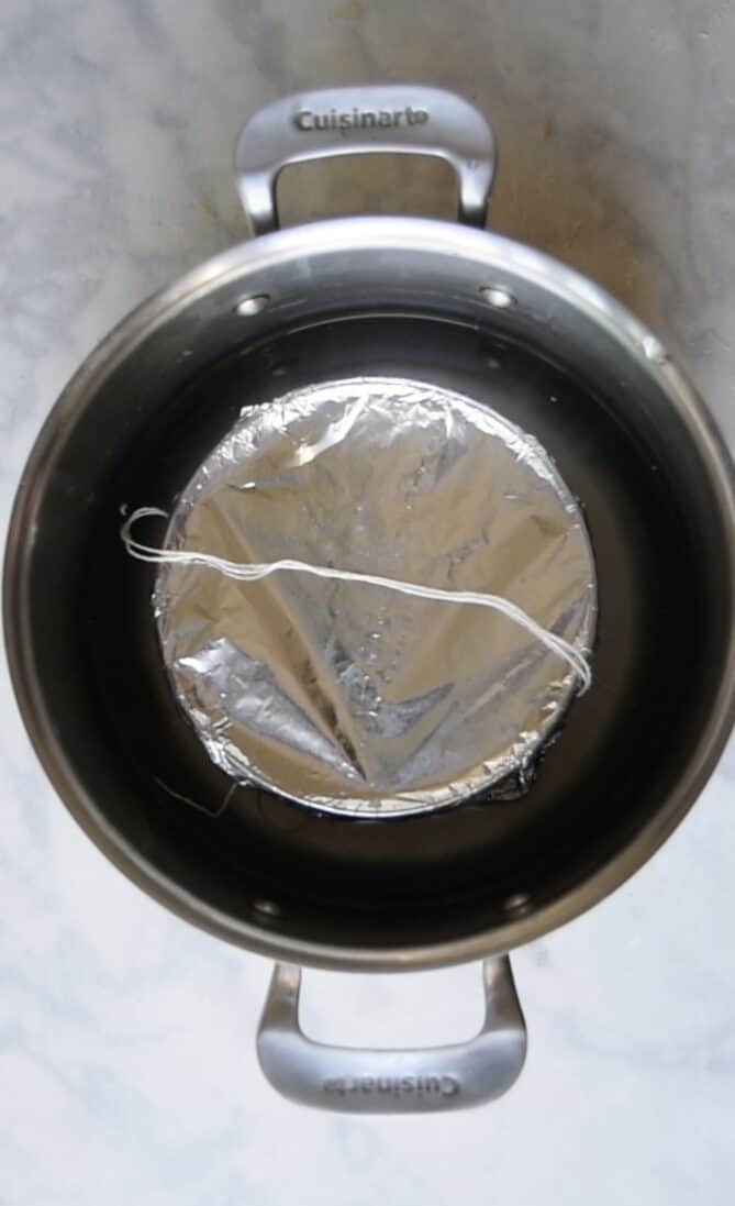 A foil covered bowl in a pan of water ready to steam