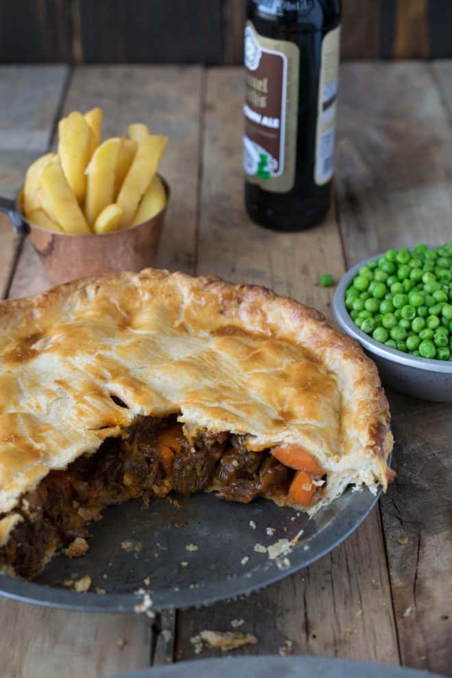 A steak and ale pie with a piece cut showing the chunky filling