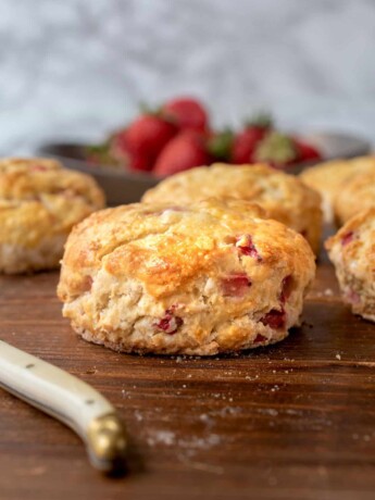 The side of a British scone dotted with fresh strawberries.
