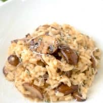 Hearty brown mushrooms mixed into creamy risotto on a white place