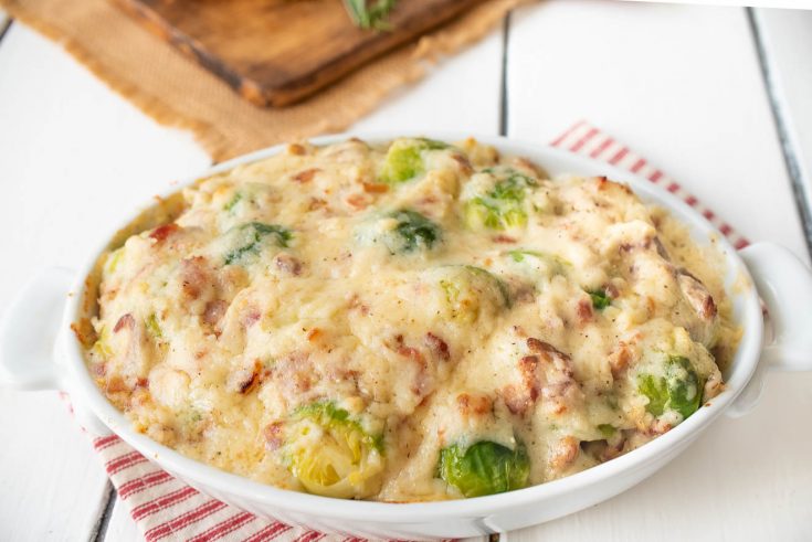 A white oval baking dish filled with Brussels sprouts and bacon cheese sauce
