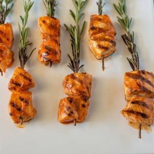 Grilled chicken with buffalo sauce skewered on rosemary sprigs