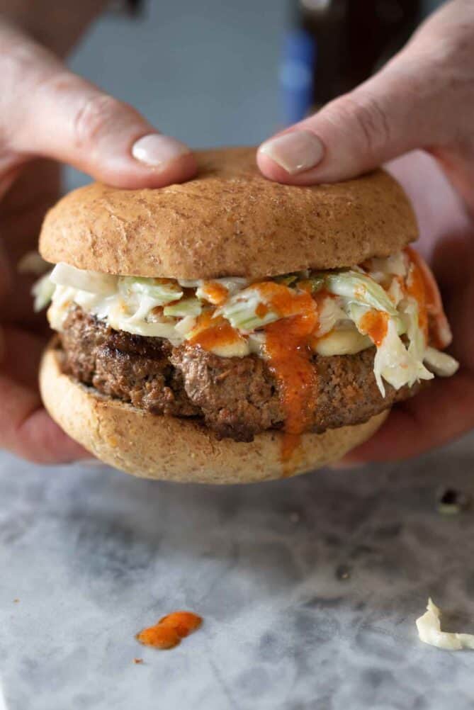 Holding a burger with hot sauce dripping