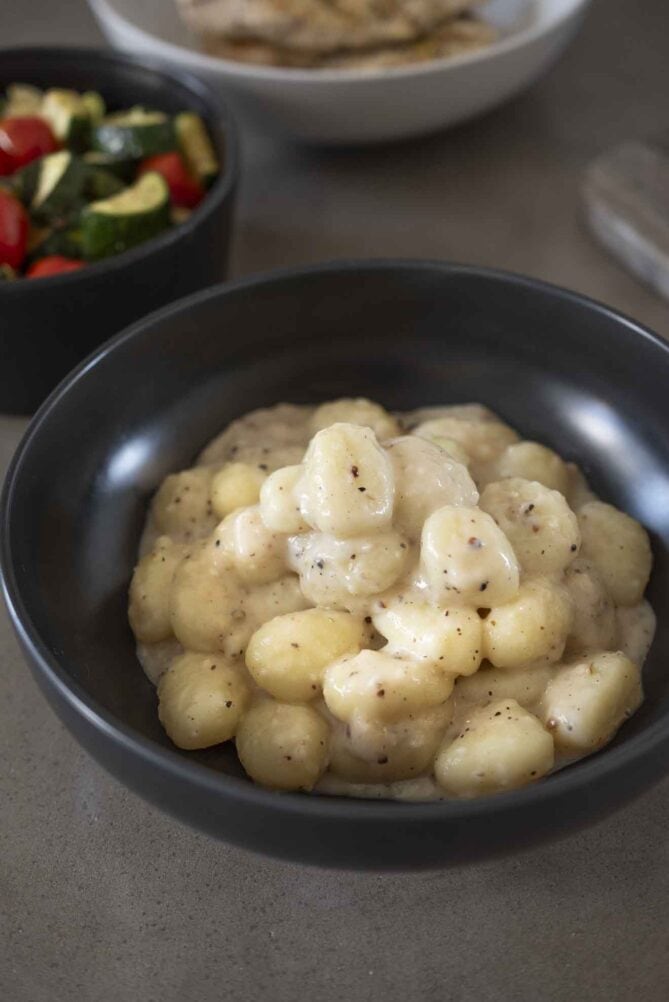 Gnocchi piled into a bowl covered in a creamy cheese sauce