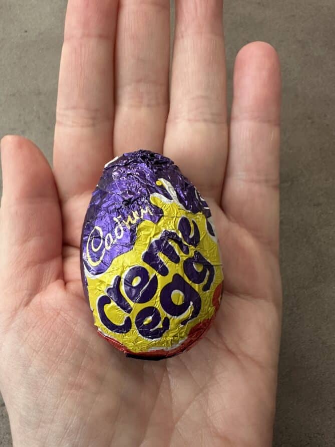 Holding a Cadbury creme egg in the palm of a hand