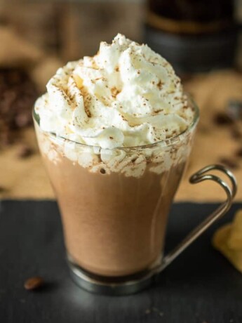 A cafe mochachino in a glass mug topped with whipped cream