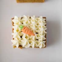 Pretty piped cream cheese frosting on top of carrot cake with a decorative sugar carrot