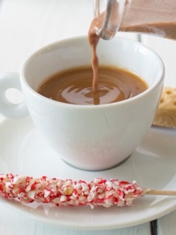 Pouring the creamer into a white cup on a saucer