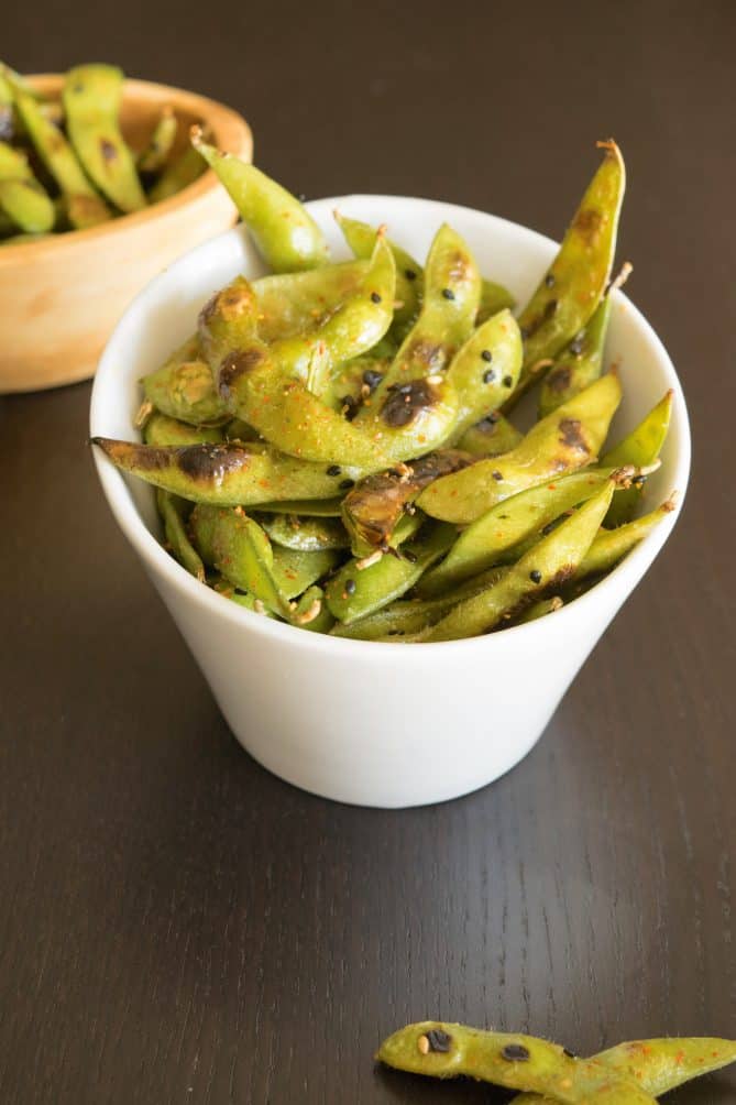 An angled white bowl filled with charred edamame