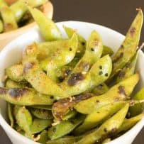 A large white bowl of edamame that has been charred and coated in togarashi spice