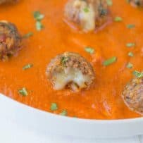 A closeup of a mini meatballs showing the melted cheese inside