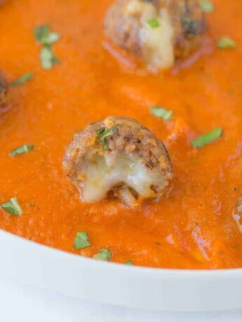 A closeup of a mini meatballs showing the melted cheese inside