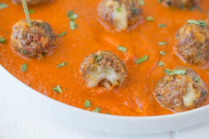 A closeup of a mini meatballs showing the melted cheese inside