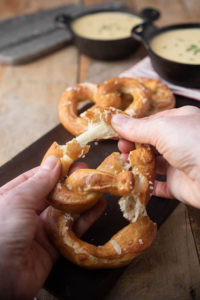 Pulling apart a pretzels showing the melted cheese inside