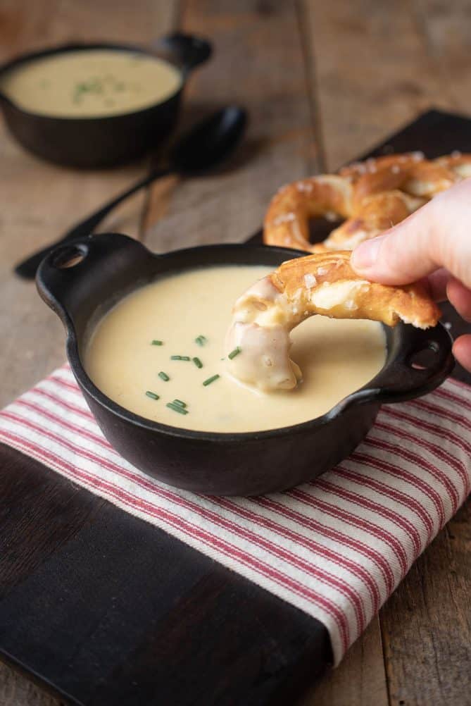 Dipping a piece of soft pretzel in a bowl of beer cheese soup
