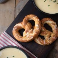 2 cheese stuffed pretzels on a board served with soup