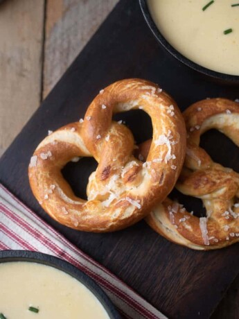 2 cheese stuffed pretzels on a board served with soup