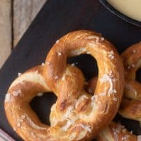 Freshly baked pretzels on a board topped with coarse sea salt